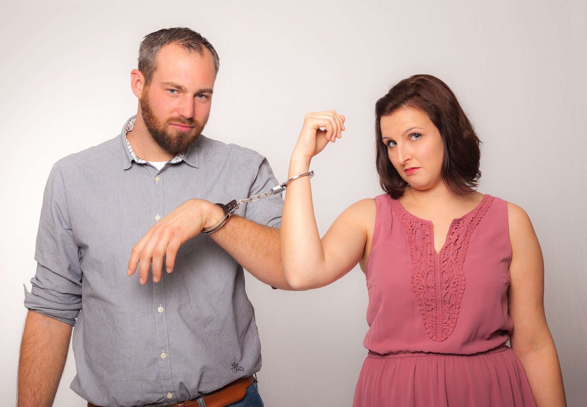Couple handcuffed together looking displeased