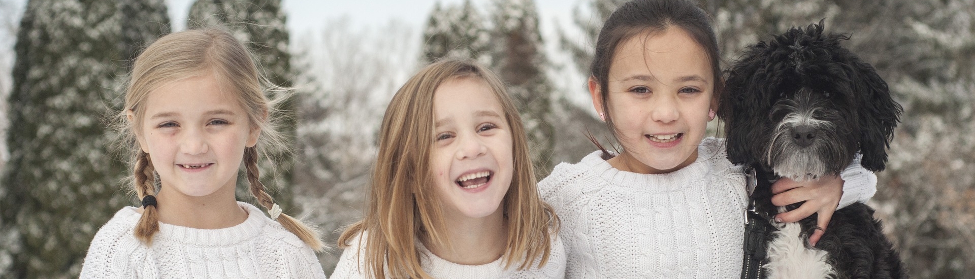Three young children and a dog smile and laugh