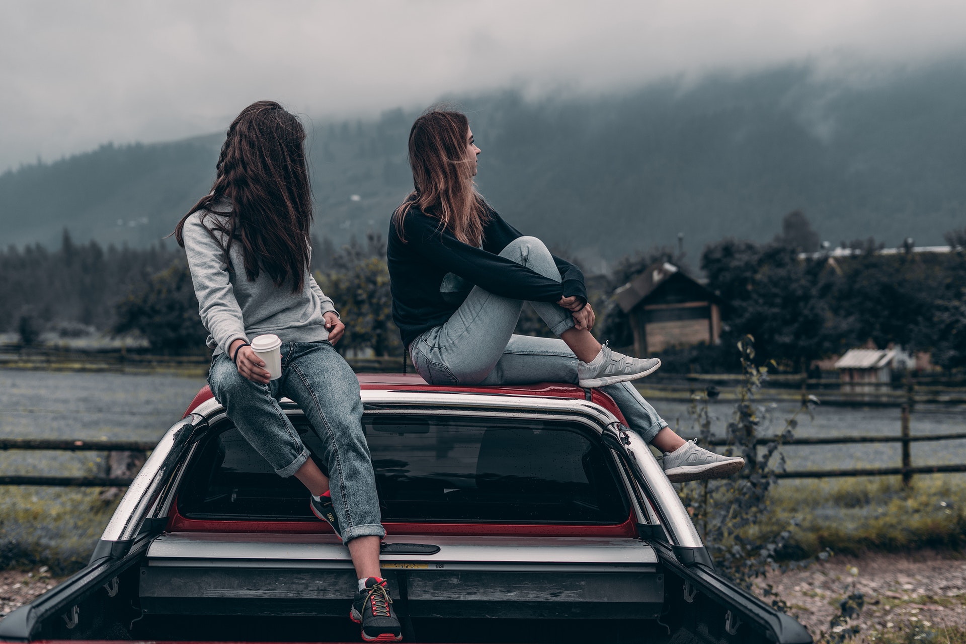 Two young women sitting on a car
