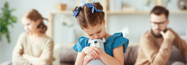 A sad child listens to her parents argue.
